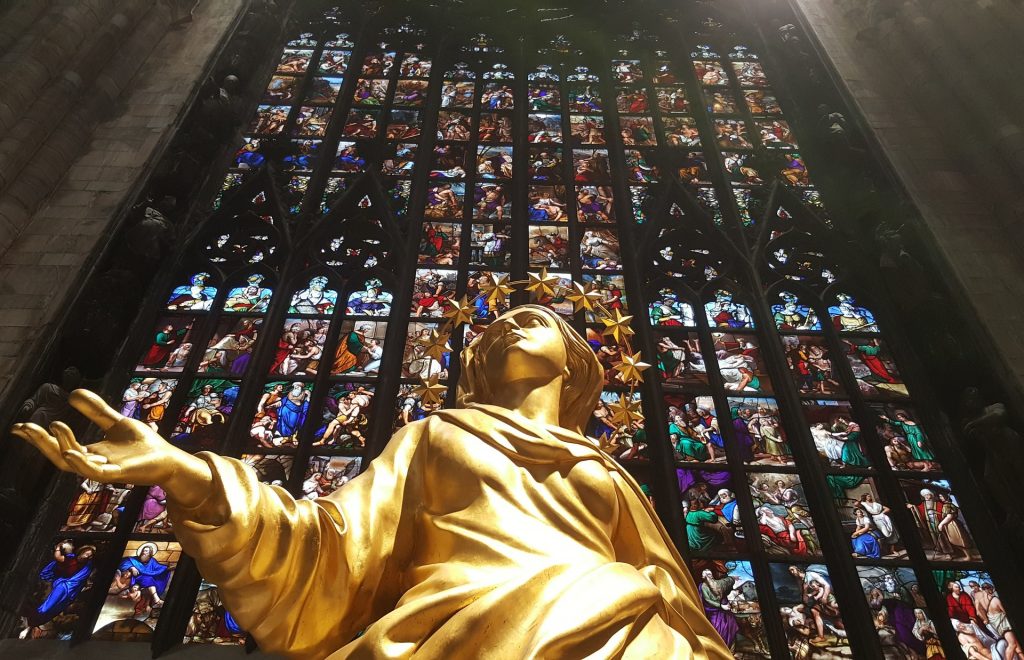 Réplica de la Madonnina de Oro junto a los vitrales del Duomo de Milán